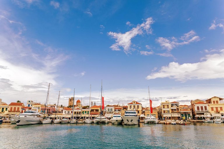 Boats moored along a curved harbourfront lined with pastel-coloured buildings