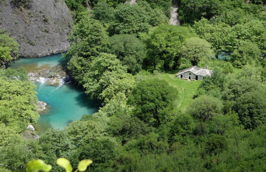 Turquoise river winding through dense green trees, seen from above
