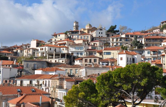 Tiled-roof houses of Arachova climbing the slope to the bell towers and dome of Agios Georgios at the top of the town