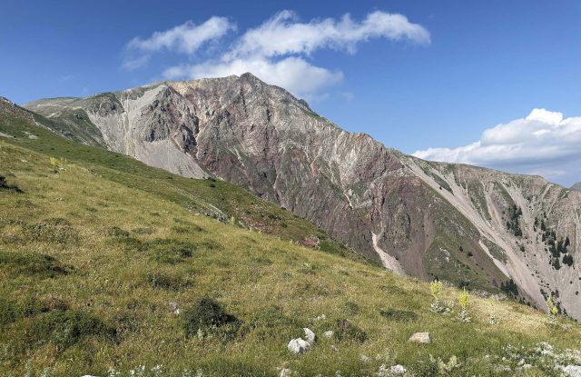 The bare summit of Mount Tymfristos above a grassy slope, seen from the road to the ski centre