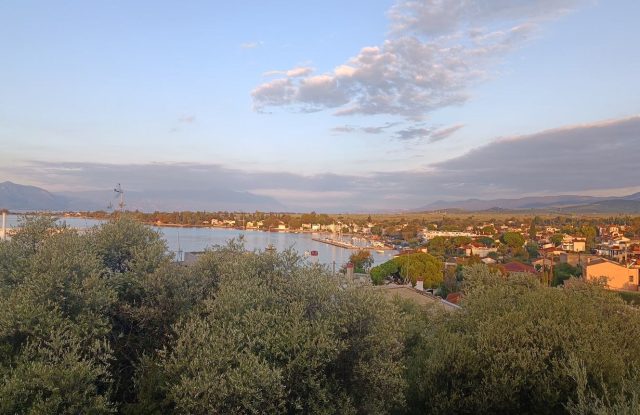 Seaside village of Raches along a curved bay with a small harbour, seen from a hill above the trees