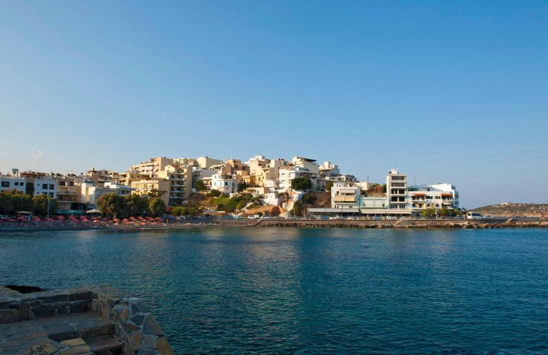 Aerial view of a bay town with colourful buildings clustered along the waterline
