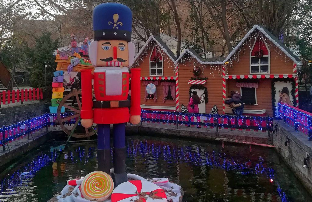 Giant nutcracker soldier decoration beside festively lit houses at the "Dream City" Christmas park in Drama.