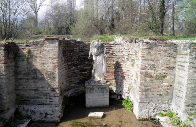 Marble statue standing among the ruined brick walls of an ancient sanctuary