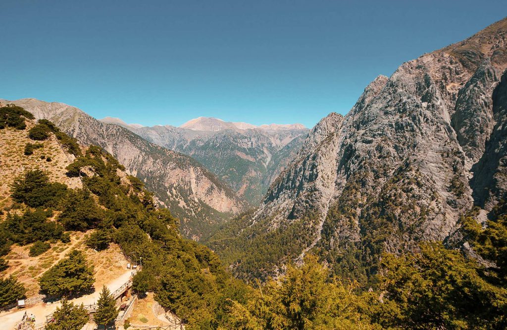 Gorge with forested slopes seen from above, with rocky peaks on both sides