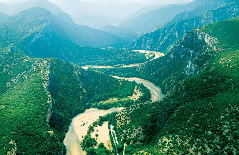 Aerial view of a river making tight bends between steep wooded slopes, with sandbanks on the inside of the bends