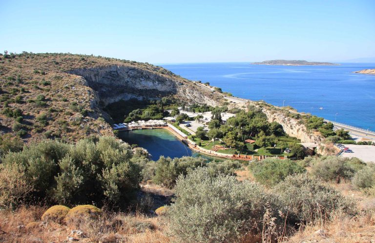 Turquoise lake enclosed by cliffs, with buildings nearby