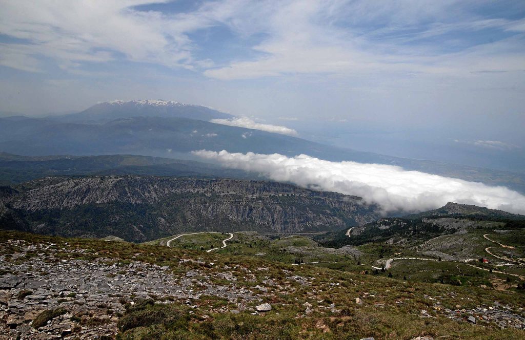 Distant massif of Mount Olympus above a band of cloud, seen across the rocky slopes of Mount Ossa