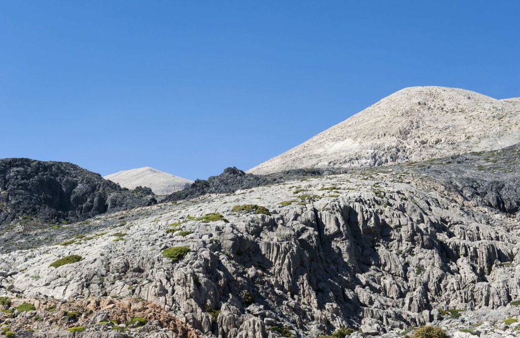 Bare pale summit rising above grey rocky ground with no vegetation